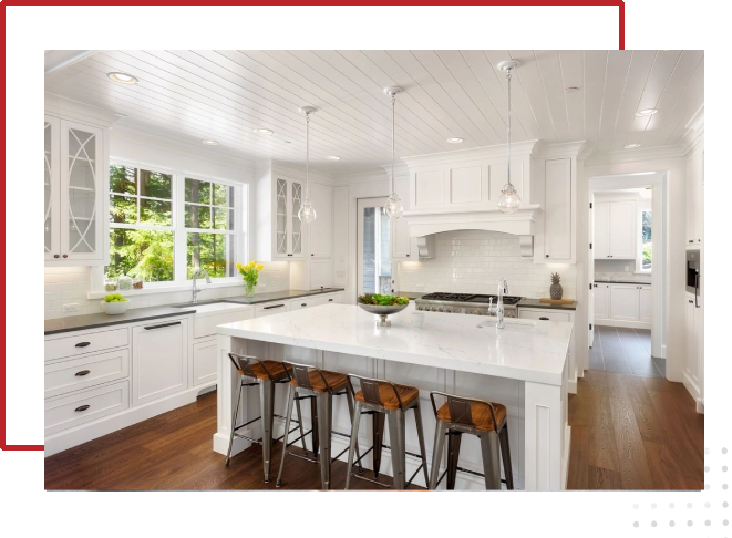 A kitchen with white cabinets and wooden floors.