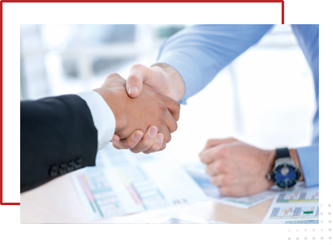 Two people shaking hands over a table.