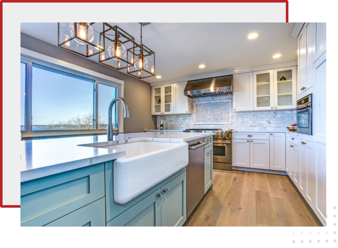 A kitchen with white cabinets and wooden floors.