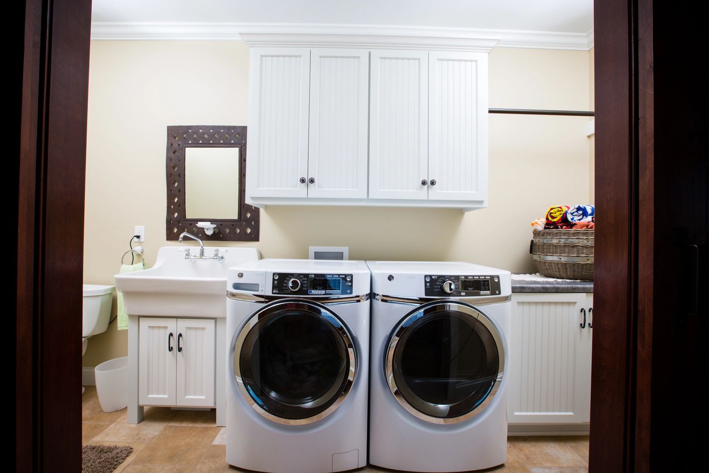 A white laundry room with two machines and sink.