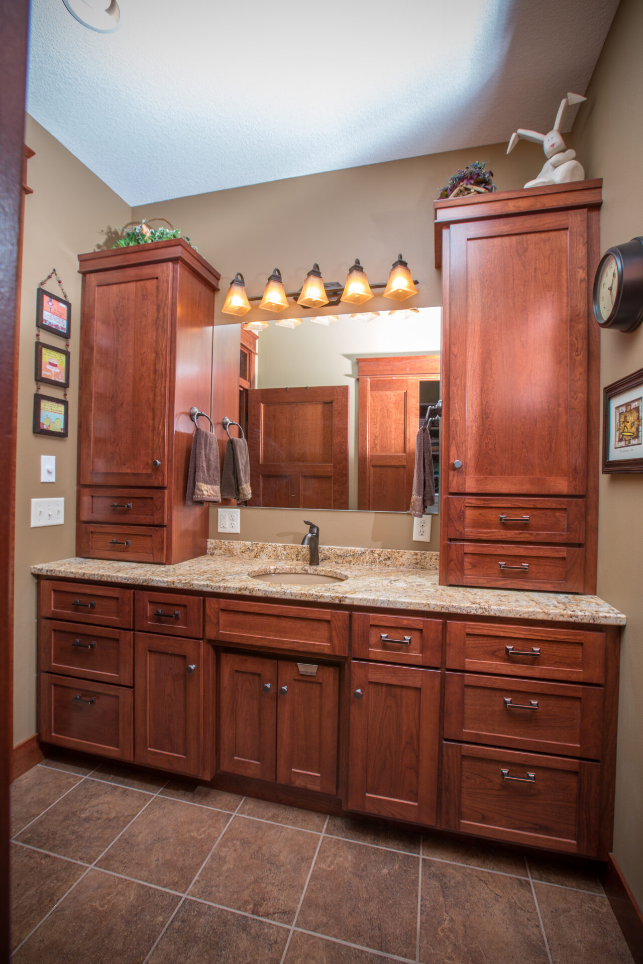 A bathroom with wooden cabinets and marble counter tops.