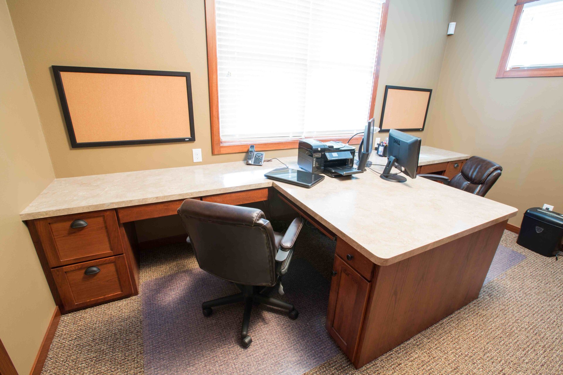 A desk with two monitors and a chair