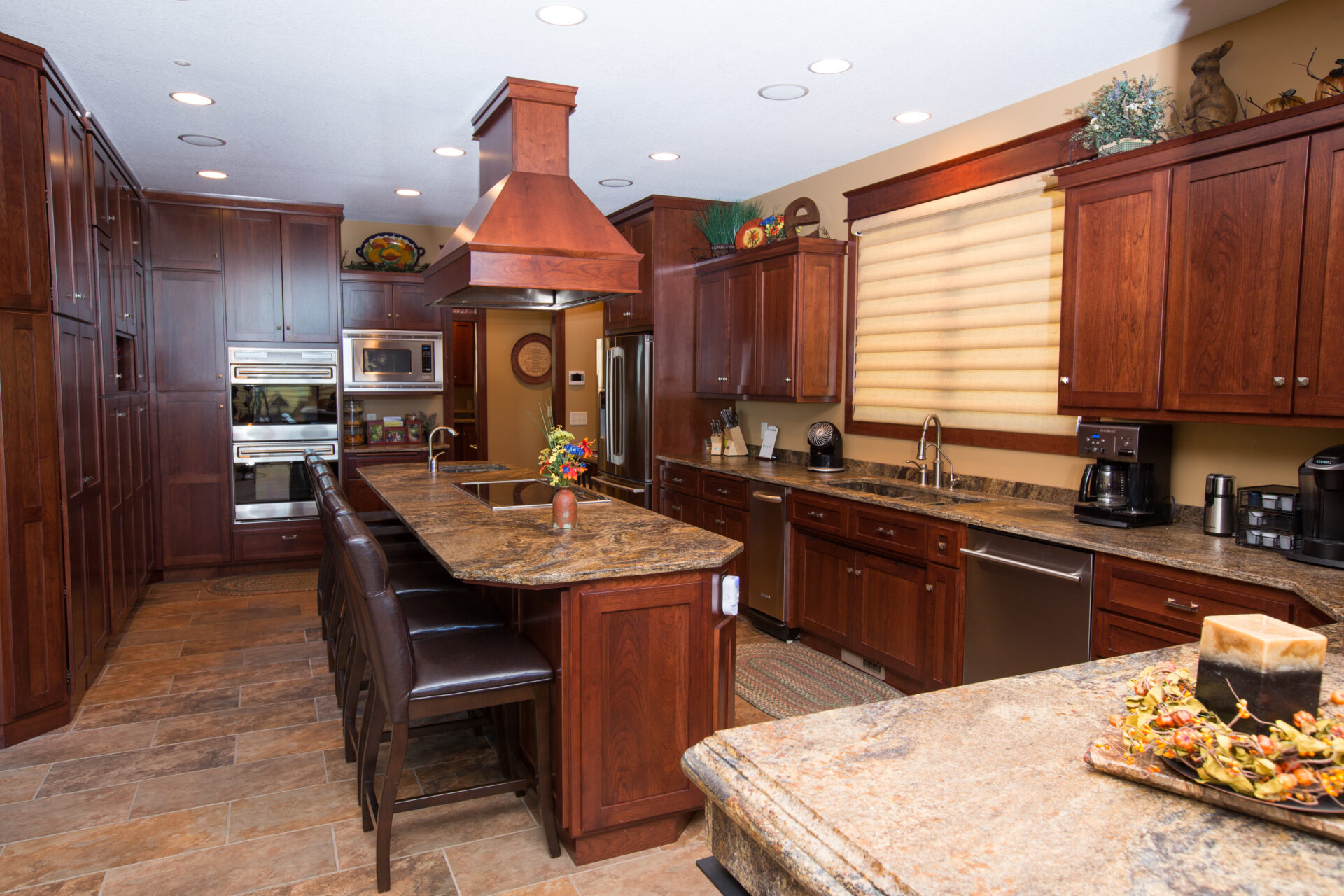 A kitchen with wooden cabinets and brown tile floors.