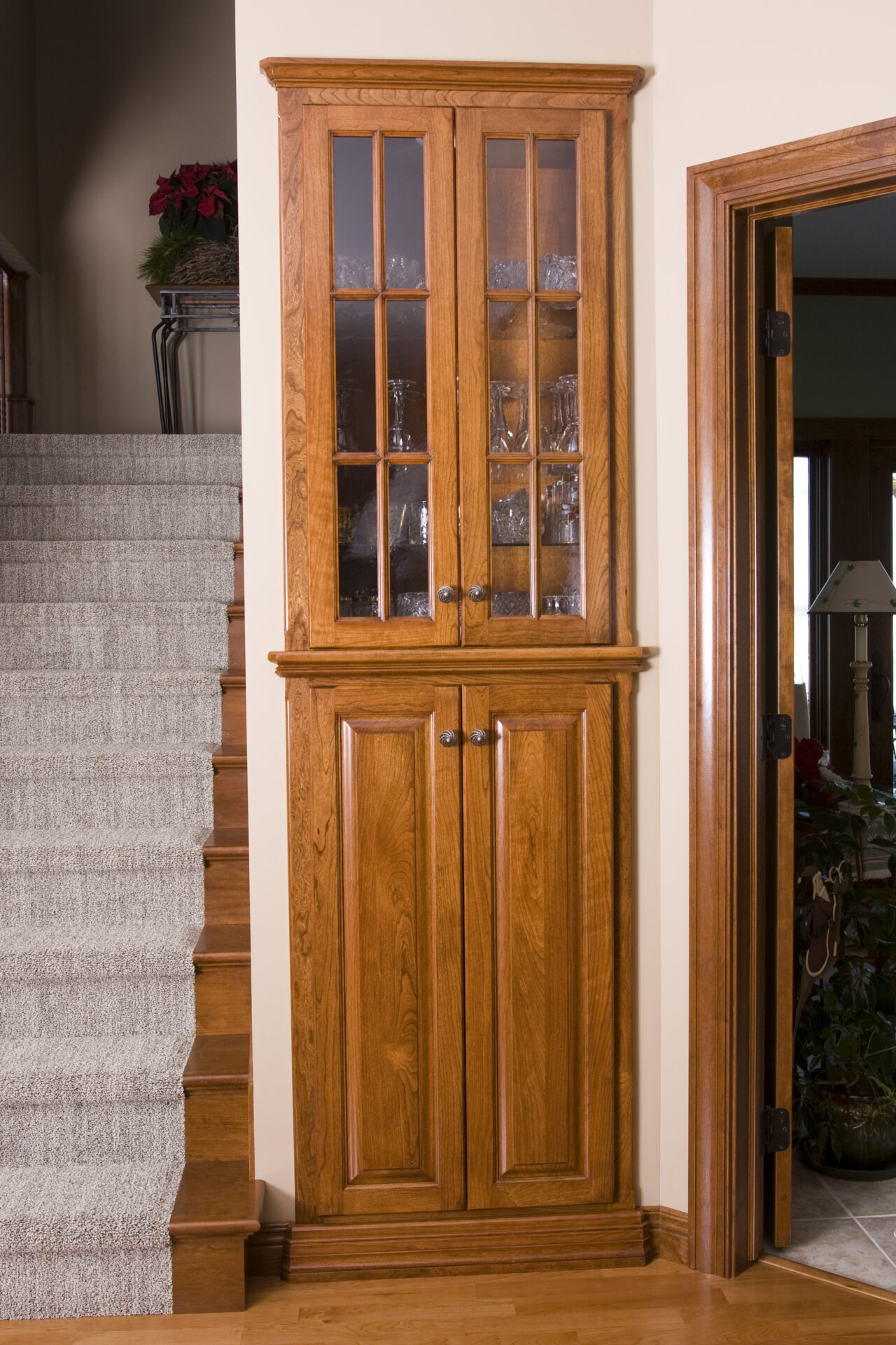 A corner cabinet with glass doors and drawers.