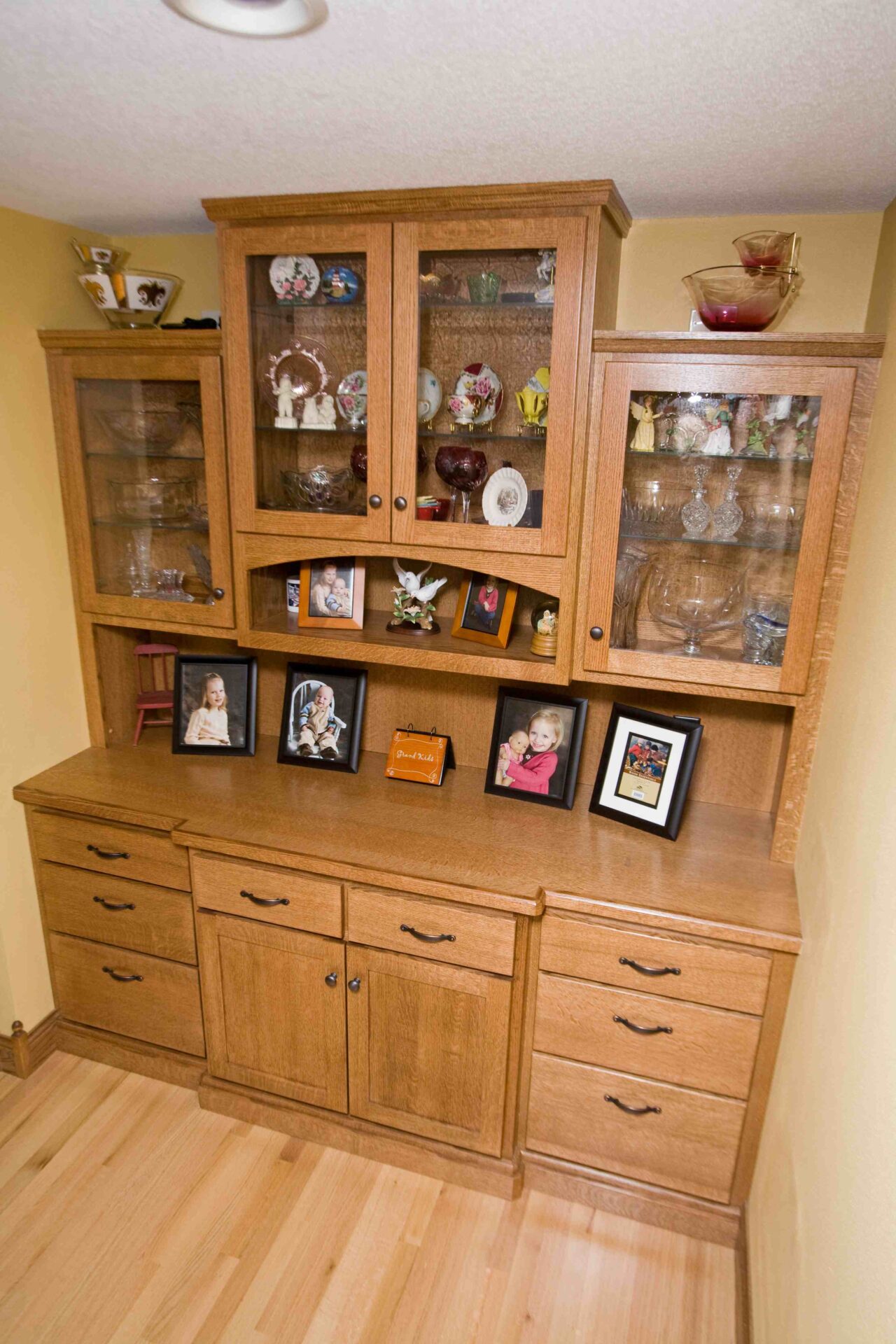 A wooden cabinet with glass doors and shelves.