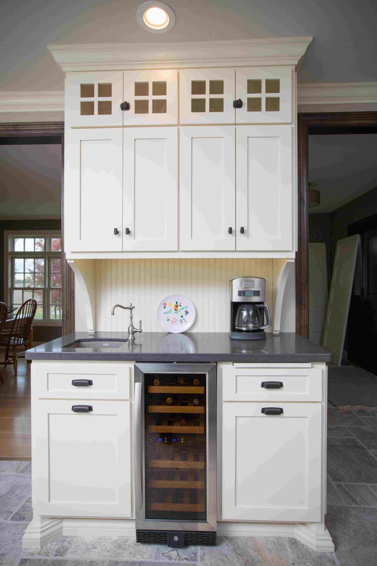 A kitchen with white cabinets and black counter tops.